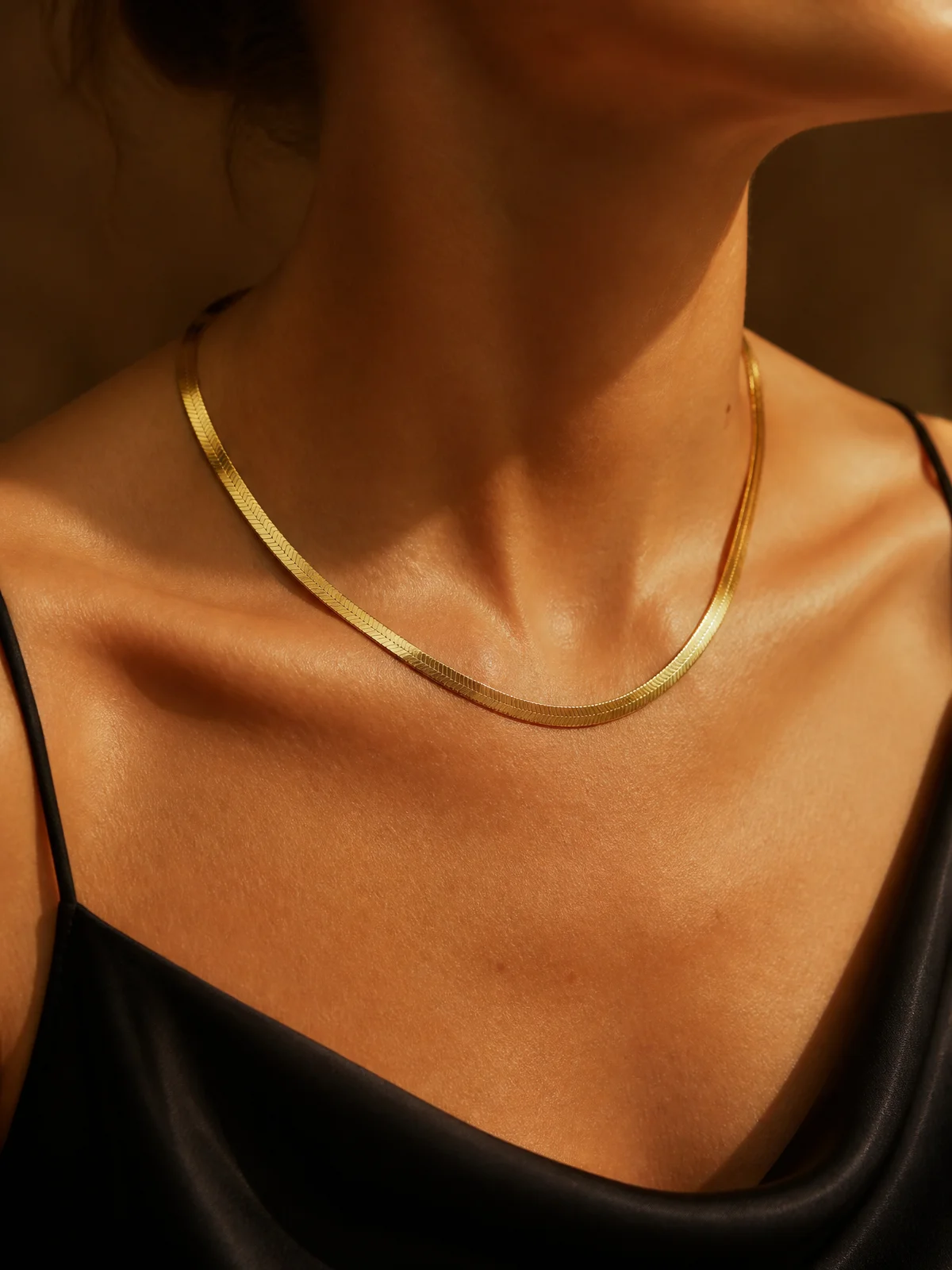 Gold vermeil herringbone chain necklace worn at the collarbone.