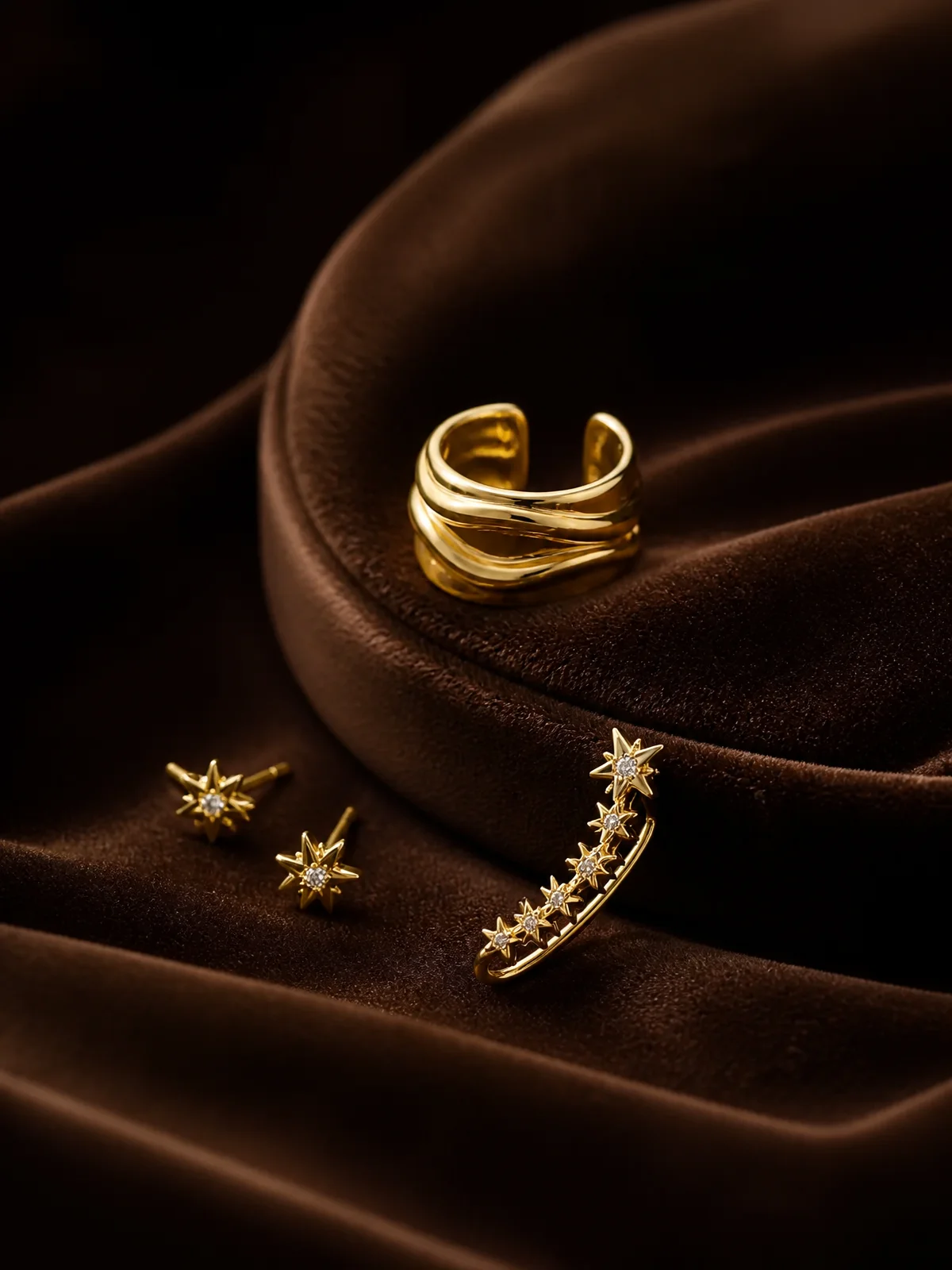 Gold vermeil ear cuff, star studs and climber earring on brown velvet.